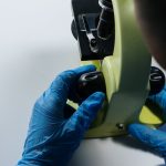 Close-up of a scientist adjusting a microscope with gloved hands in a laboratory.